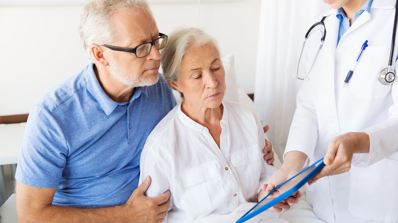 An older couple being shown an iPad with medical information by a doctor